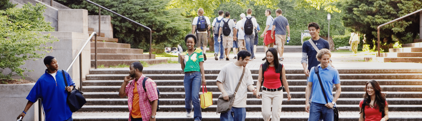 Group of students walking and smiling on campus steps and chatting with each other