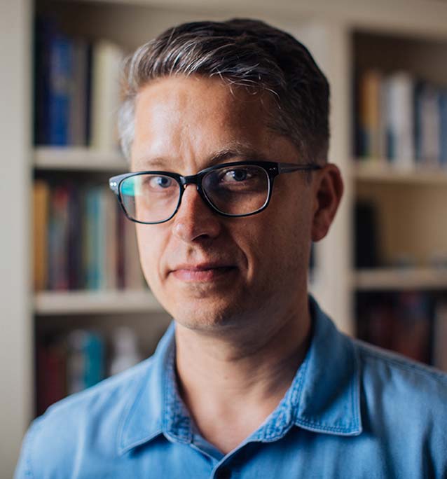 Chris Bone standing in front of a book case