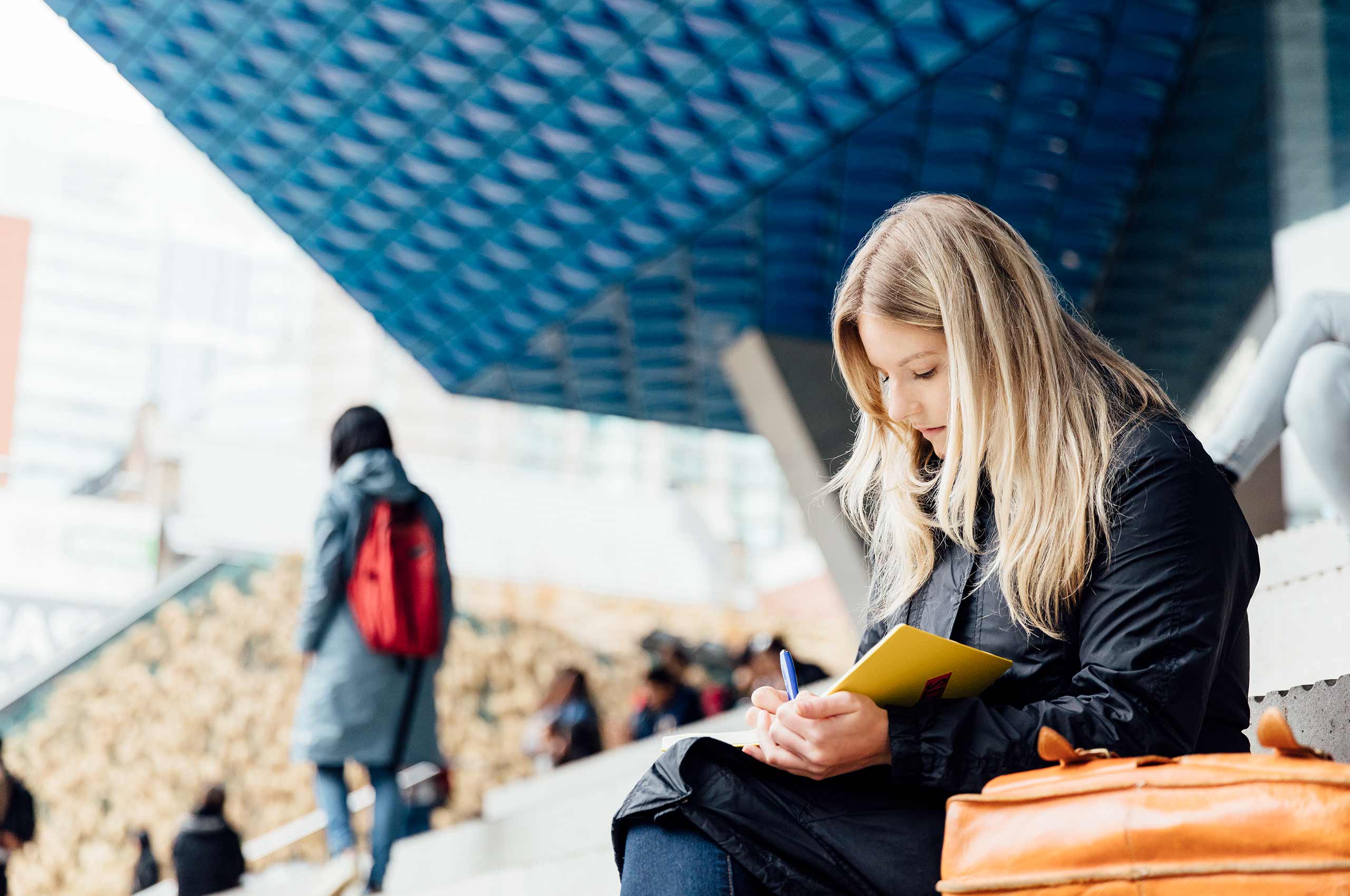 Student sitting on the steps writing in her notebook