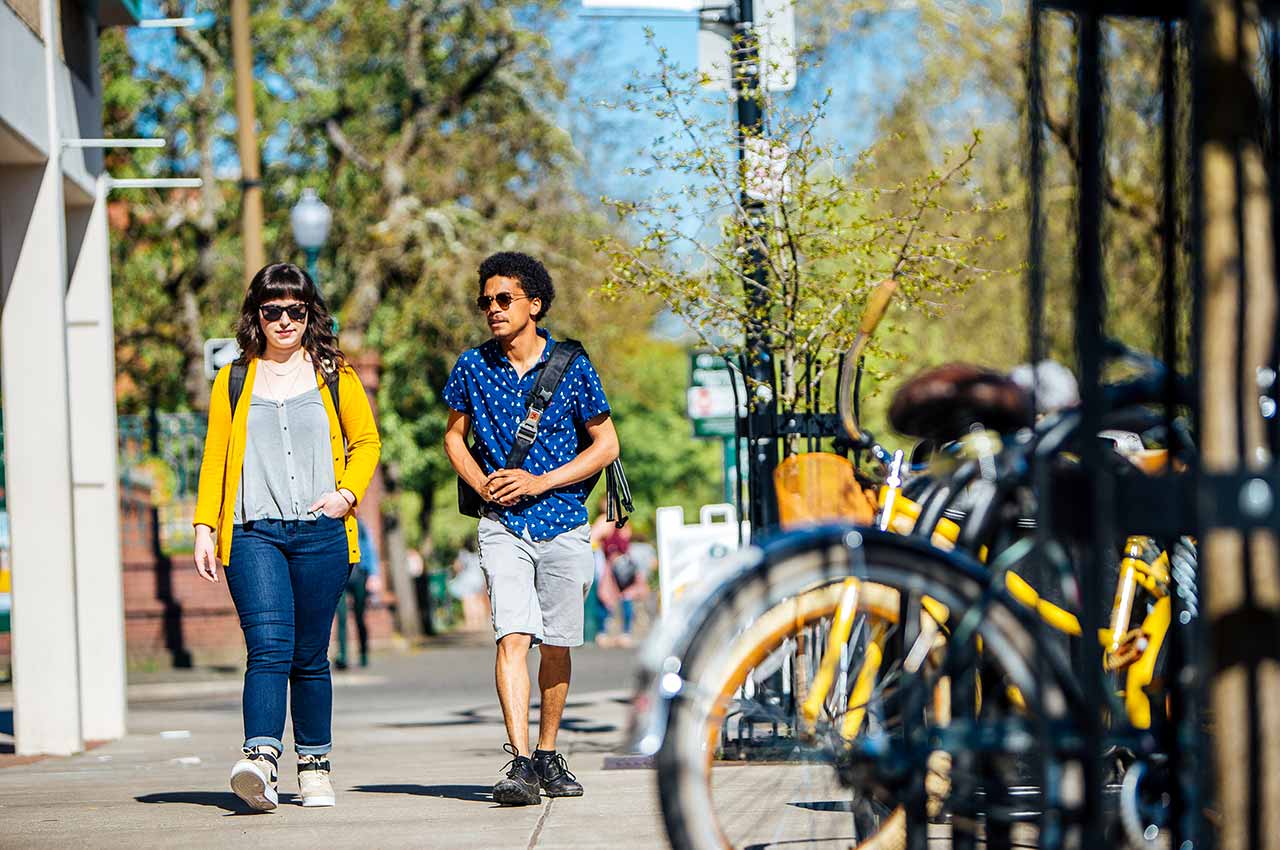 Two hip students walking down the street on a sunny day