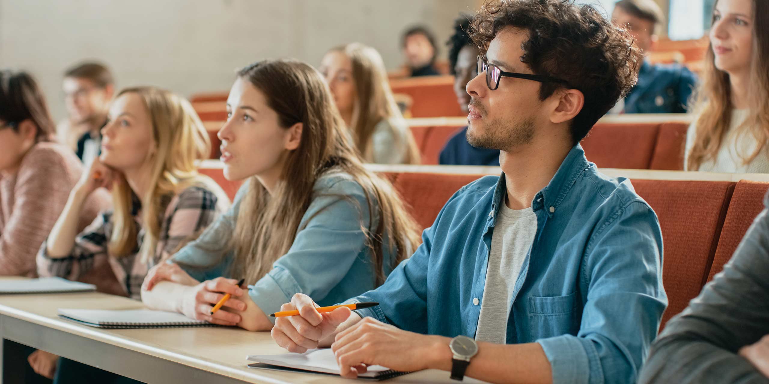  A group of diverse students sitting in a lecture hall, listening attentively to the professor.